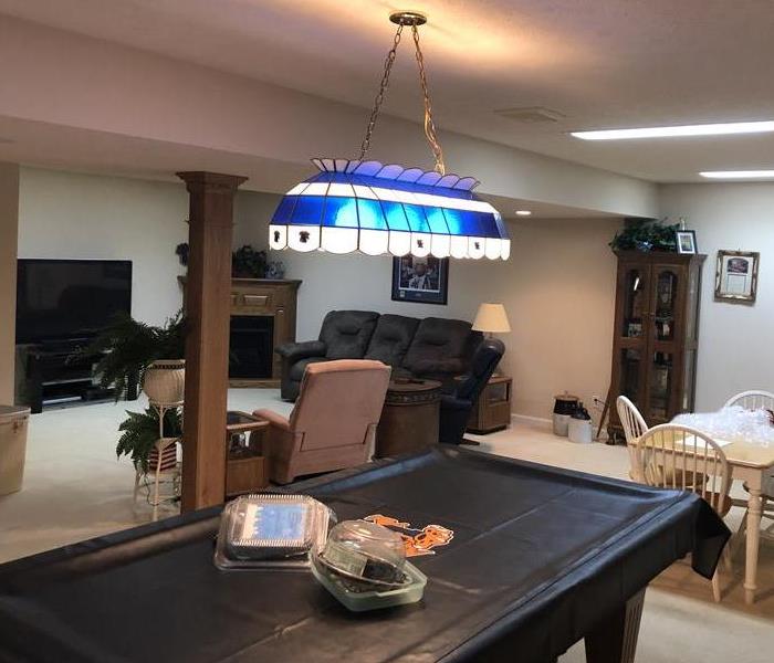 Pool Table, Brown sofa, Cream carpet, Kitchen table, blue/white lighting fixture over pool table, brown column, brown hutch