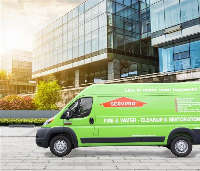 SERVPRO vehicle parked in front of glass buildings in a city atmosphere.
