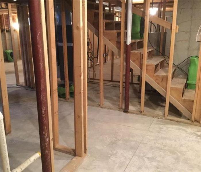Drywall and flooring removed in a basement with SERVPRO equipment placed in affected areas. 