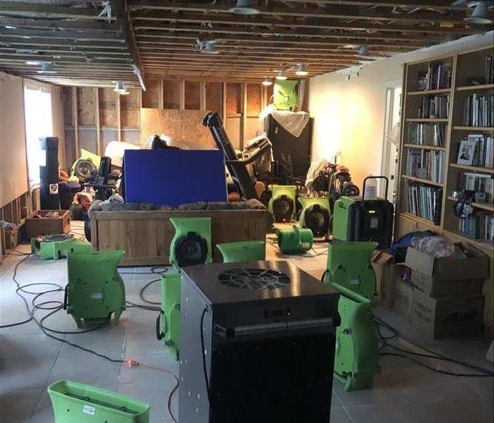 Grey tile floors, wood beams in walls exposed, 3 large filled bookcases, 13 SERVPRO air movers throughout the room